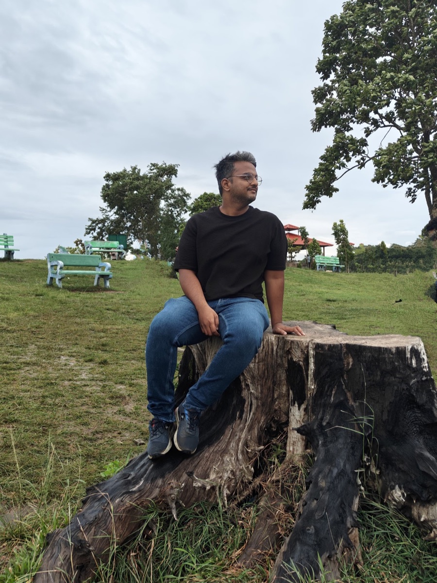 Himavanth sitting on a tree stump in a hillside park